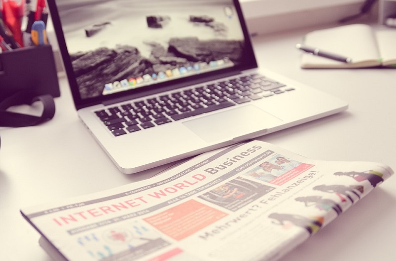 a laptop and a newspaper on a desk